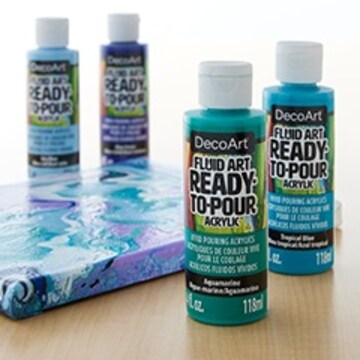 DecoArt pouring painting bottles in blue green and purple sitting next to finished pouring art canvas